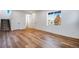 Spacious living area featuring light wood floors, white walls, several doors, a staircase, and a large window at 17822 E 107Th Pl, Commerce City, CO 80022