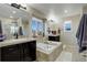 Bright bathroom featuring a soaking tub, separate shower, and dual vanities with dark cabinets at 10265 Olathe St, Commerce City, CO 80022