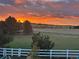 Enjoy breathtaking sunset views from this property, featuring a spacious green backyard and charming white fence at 2996 Savage Rd, Elizabeth, CO 80107