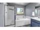 Bright bathroom featuring a soaking tub, a shower, and a vanity with blue cabinets and tile flooring at 2996 Savage Rd, Elizabeth, CO 80107