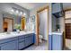 Bathroom featuring double sinks with blue cabinets, decor, and an open doorway to the toilet and built-in shelving at 2996 Savage Rd, Elizabeth, CO 80107