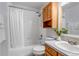 Bathroom with white tile walls, wood cabinets and a vanity plus a tub/shower and a white shower curtain at 2996 Savage Rd, Elizabeth, CO 80107