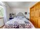 Bedroom with neutral paint, window, and a bed featuring a gray tufted headboard, patterned quilt, and wooden doors at 2996 Savage Rd, Elizabeth, CO 80107