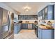 Updated kitchen features blue cabinets, stainless appliances, beautiful countertops and chevron-patterned floors at 1655 S Lowell Blvd, Denver, CO 80219