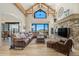 Comfortable living room features a stone fireplace, large windows with mountain views, and a brown leather sectional at 12963 Silver Elk Ln, Littleton, CO 80127