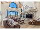 Inviting living room with stone fireplace, large windows with mountain views, and a comfortable brown leather sectional at 12963 Silver Elk Ln, Littleton, CO 80127
