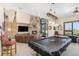 Spacious living room featuring a stone fireplace, pool table, and comfortable seating area with natural light at 12963 Silver Elk Ln, Littleton, CO 80127