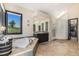 Bright primary bathroom with a soaking tub, shower with glass block wall, and a double vanity at 12963 Silver Elk Ln, Littleton, CO 80127