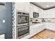 Modern kitchen featuring stainless steel appliances, granite counters, white cabinets, and hardwood floors at 17335 W 94Th Ave, Arvada, CO 80007