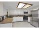 Well-lit kitchen with white cabinets, stainless steel appliances, and tile countertops at 12089 W Burgundy Ave, Littleton, CO 80127