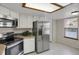Bright kitchen area with stainless steel refrigerator, oven, microwave, and white cabinetry at 12089 W Burgundy Ave, Littleton, CO 80127