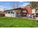 Large backyard featuring a patio with seating, a well-maintained lawn, and mature trees at 5856 Simms St, Arvada, CO 80004