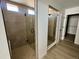 A contemporary bathroom with glass shower, neutral tiles, and a glimpse into the walk-in closet at 25343 E Warren Pl, Aurora, CO 80018