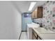 Functional laundry room with washer, dryer, sink, and storage cabinets with colorful wallpaper at 3269 W 101St Cir, Westminster, CO 80031