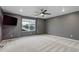 Spacious bedroom with gray walls, plush carpeting, ceiling fan and a large window offering neighborhood views at 9250 Rifle St, Commerce City, CO 80022