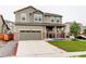 Two-story home with a two car garage, landscaped yard, and a covered porch at 9250 Rifle St, Commerce City, CO 80022