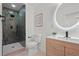 Bathroom featuring tiled shower, toilet, and vanity with a modern faucet and circular mirror at 3025 Ivanhoe St, Denver, CO 80207