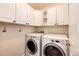 Well-lit laundry room with white cabinetry and modern appliances at 3841 Colorful Ln, Castle Rock, CO 80109