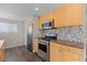 Well-lit kitchen features stainless steel appliances, tile backsplash, gas range, and ample cabinet space at 1996 S Dexter St, Denver, CO 80222