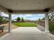 A covered patio looks out to a spacious backyard with a well maintained lawn and privacy fence at 3029 Merlin Dr, Brighton, CO 80601