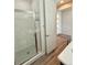 A bathroom with a glass shower, and hardwood floors leading to the front door at 3029 Merlin Dr, Brighton, CO 80601