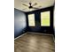 This bedroom has dark blue walls, light wood floors, a ceiling fan, and bright windows at 3029 Merlin Dr, Brighton, CO 80601