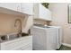 Functional laundry room with stainless steel sink, white cabinets, and modern washing machines at 10825 Mount Antero Way, Parker, CO 80138
