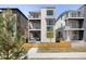 Modern three-story home featuring private balconies, stone accents, and a wooden fence, enhancing curb appeal at 21418 E 61St Dr, Aurora, CO 80019