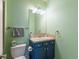 Well-lit bathroom with green walls, blue vanity, white toilet, and tile flooring at 8985 E 29Th Pl, Denver, CO 80238