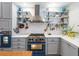 Modern kitchen with stainless steel range hood, open shelving, and a stylish blue oven at 8985 E 29Th Pl, Denver, CO 80238