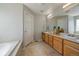 Bathroom featuring double sinks, wooden cabinets, and a separate soaking tub at 6786 Halifax Ave, Castle Rock, CO 80104