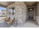Charming front porch with stone columns, comfortable chairs, and a stylish outdoor rug at 2040 Rosette Pl, Castle Rock, CO 80104