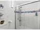 Modern shower with glass doors, wall-mounted shower head, white tile and blue accents at 4842 Steele St, Denver, CO 80216