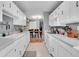 Galley kitchen with white cabinets and appliances that leads to dining area at 7973 Chase Cir # 56, Arvada, CO 80003