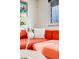 Close up of the bright orange sofa with decorative pillows and a side table near the window at 1308 W 102Nd Ave, Northglenn, CO 80260