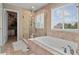 Elegant bathroom featuring a soaking tub, glass-enclosed shower, and a view from the large window at 8182 Grady Cir, Castle Rock, CO 80108
