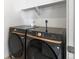 A laundry room featuring modern black Samsung washer and dryer units with gold accents for contemporary appeal at 928 Farrier Ln, Lafayette, CO 80026