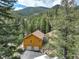 Aerial view of cabin with two-car garage and lots of trees and mountain views at 1353 Elk Valley Dr, Evergreen, CO 80439
