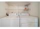 Functional laundry area with a full-size washer and dryer and wire shelving for storage at 5465 Zephyr St # 201, Arvada, CO 80002