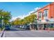 Charming street view with brick buildings, mature trees, and parked cars along a sunny street at 5465 Zephyr St # 201, Arvada, CO 80002