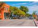 Charming street with colorful building, outdoor seating, mature trees, and parked cars along a sunny street at 5465 Zephyr St # 201, Arvada, CO 80002