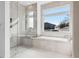 Modern bathroom with glass-enclosed shower, soaking tub, and picture window with scenic views at 17326 W 57Th Ave, Golden, CO 80403