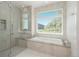 Bright bathroom featuring a modern bathtub, a glass enclosed shower, and a scenic window view at 17326 W 57Th Ave, Golden, CO 80403