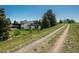 Exterior shot of a modern home with a long dirt driveway and views of the landscape at 17326 W 57Th Ave, Golden, CO 80403