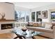 Sunlit living room with a modern fireplace, large windows offering a scenic view, and stylish decor at 17326 W 57Th Ave, Golden, CO 80403