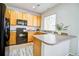 Well-lit kitchen with wood cabinets, a black appliance suite, and gray countertops at 13033 Grant E Cir # B, Thornton, CO 80241