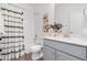 Clean bathroom featuring a tub with patterned shower curtain and a gray vanity with artwork at 2140 Santini Trl # F, Littleton, CO 80129