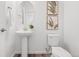 Bright half bathroom featuring a pedestal sink, framed art, and a classic toilet for a modern feel at 2140 Santini Trl # F, Littleton, CO 80129