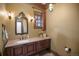 Powder room with a custom vanity, granite countertop, decorative mirror, sconce lighting, and travertine tile flooring at 4030 E Forbes Ct, Greenwood Village, CO 80121