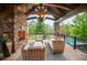 Covered patio with stone fireplace, comfortable seating, wood beams and view of pool at 4030 E Forbes Ct, Greenwood Village, CO 80121